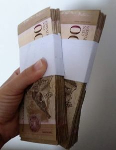 Mão segura notas de moeda venezuelana